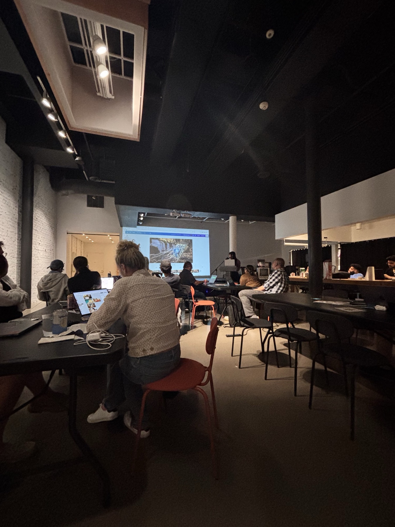 The Luma maker night room during a live agent demonstration, with attendees working on laptops.