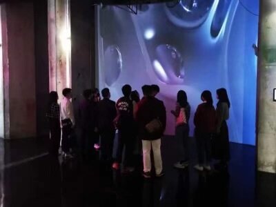 Visitors watching a chrome bubble-wall projection in a dark room