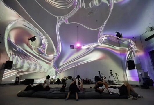 Visitors reclining under a liquid-chrome projection dome
