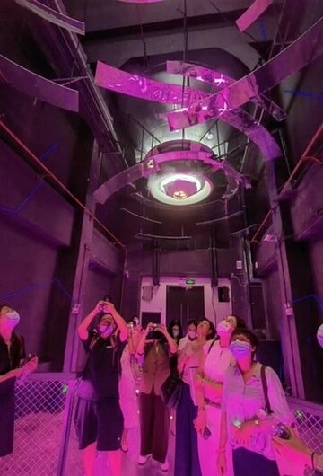 Visitors in a magenta-lit industrial corridor
