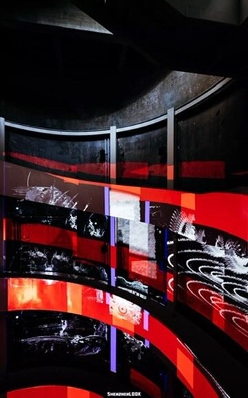 A curved red-and-black projection wall inside a silo